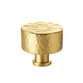 Gold cabinet knob with a textured surface on a white background